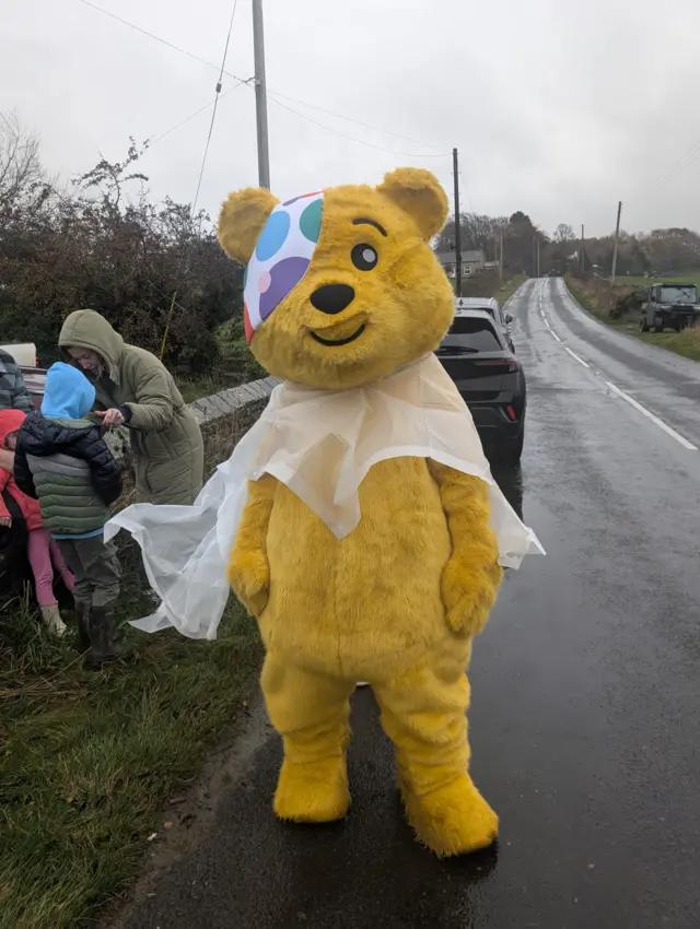 Pudsey wears a raincoat