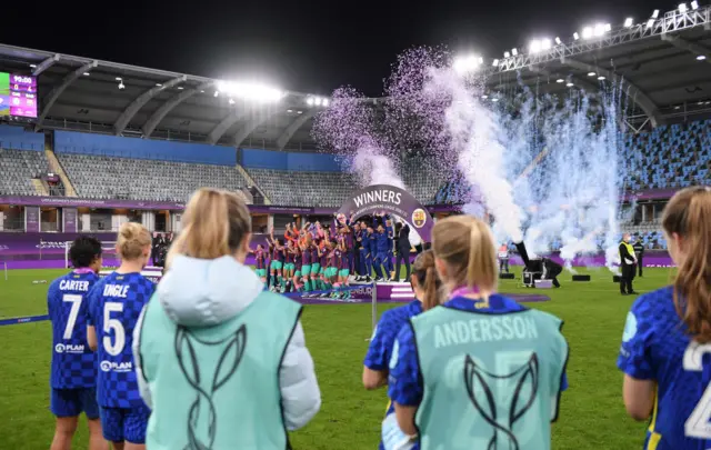 Chelsea players watch on as Vicky Losada of FC Barcelona lifts the UEFA Women's Champions League Trophy in celebration with team mates following the UEFA Women's Champions League Final match between Chelsea FC and Barcelona at Gamla Ullevi on May 16, 2021 in Gothenburg, Sweden.