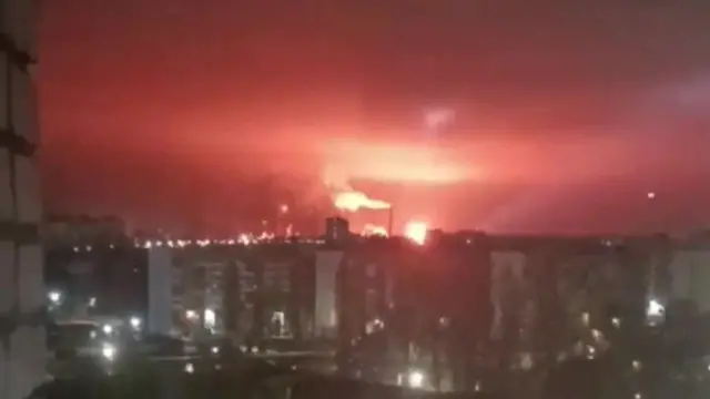 A fire burning at a oil refinery in the distance