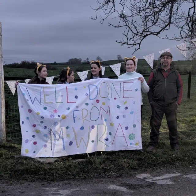 5 people hold a sign saying 'Well done from MWRA'