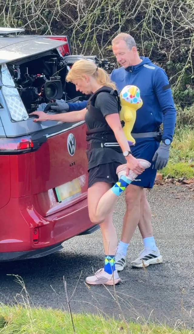 Sara Cox stretches her legs, balancing on the car.