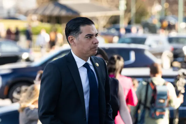 Rep. Robert Garcia, D-Calif., walks up the House steps. He wears a dark suit and tie, and is slightly frowning. People are seen behind him but out of focus.