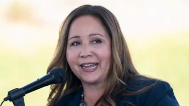 A woman with long brown hair and a blue jacket