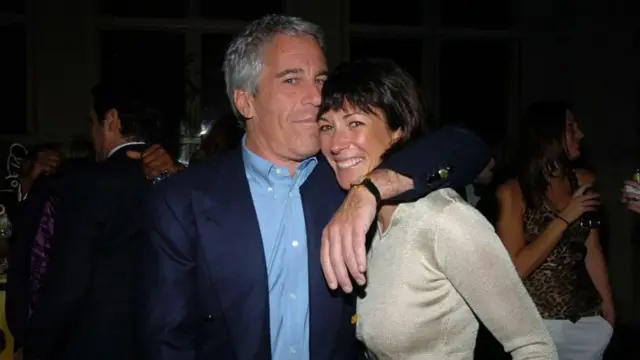 Maxwell and Epstein in a dark room smiling whilst embracing