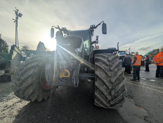 A tractor with big wheels, stood in a muddy field