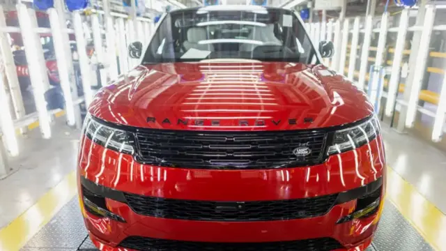 A red Jaguar Rover Sport car in the middle of a warehouse.
