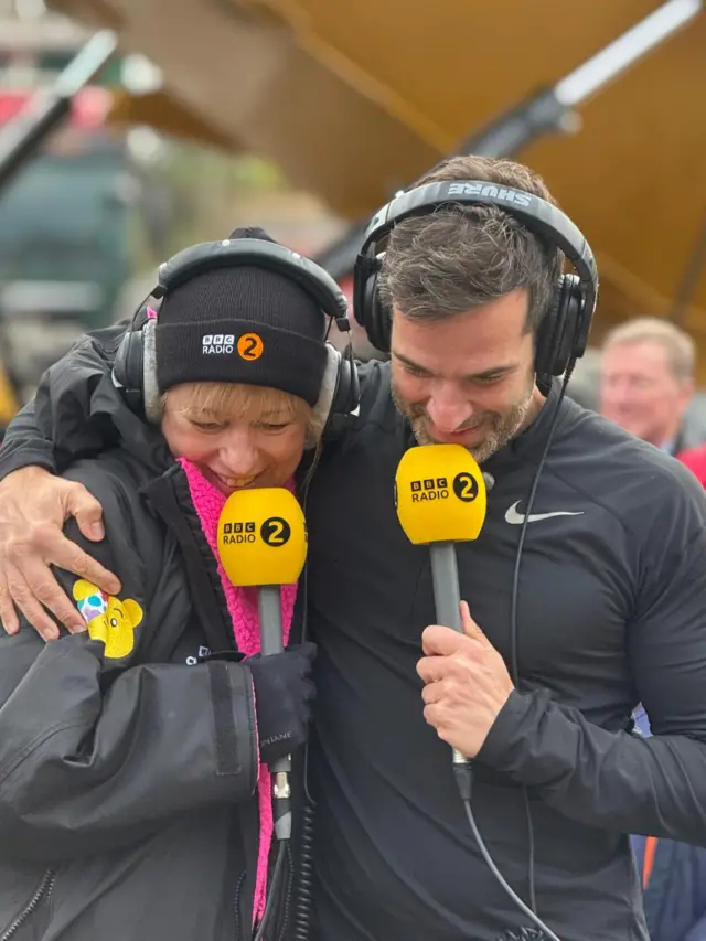 Sara and Gethin smile into radio microphones
