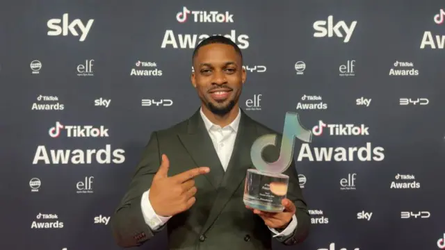 Kieran Monlouis pointing to his TikTok award