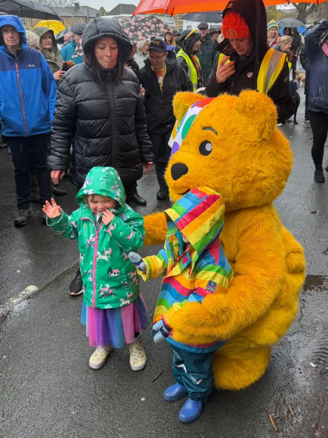 Toddlers in rainbow outfits pose with Pudsey