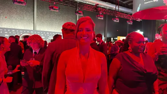 Kyra Mae Turner smiles at the camera with crowds of people behind her