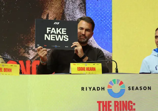 Eddie Hearn holds up a placard that says 'fake news'