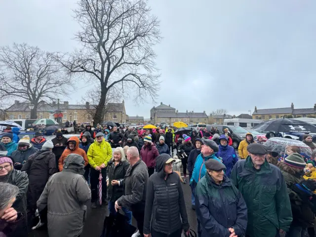 Crowds wait in the rain