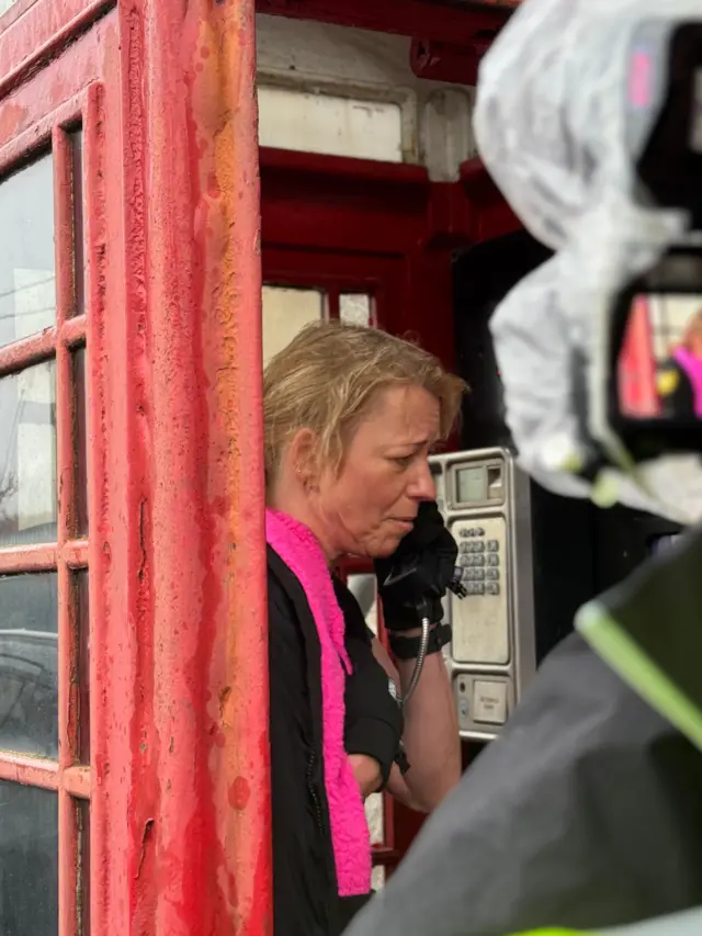 Sara Cox inside a red telephone box receiving a phone call from her mum and sister in India
