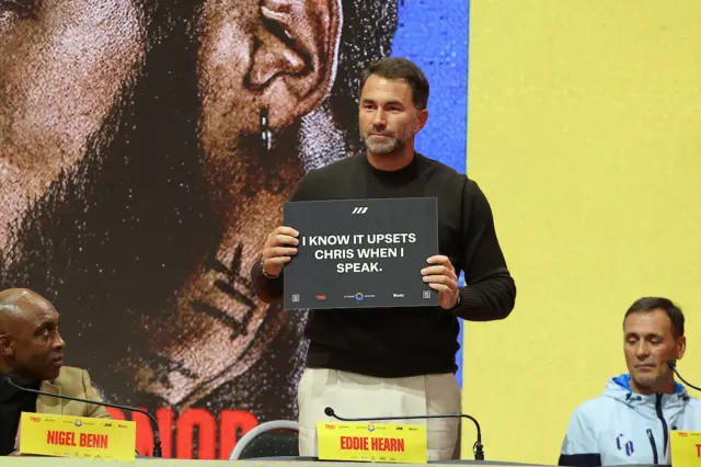 Eddie Hearn holds up a placard that says 'I know it upsets Chris when I speak'