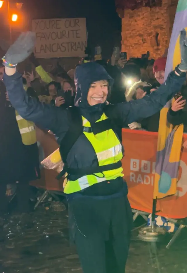 Sara raises her arms at the finish line