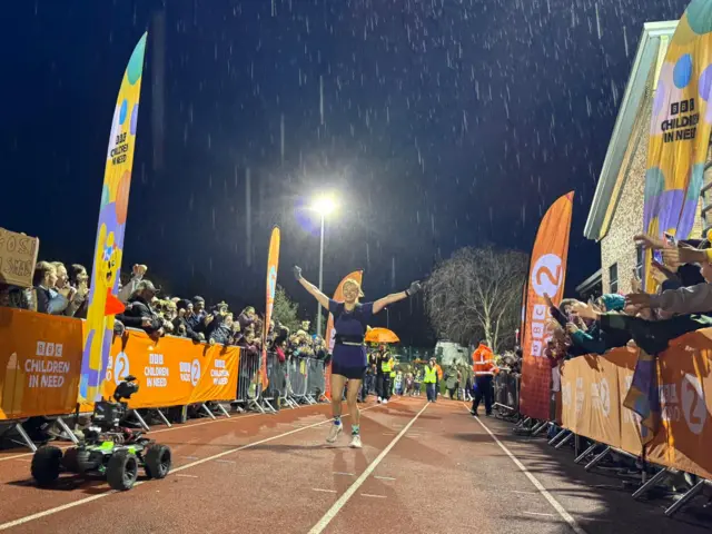 Sara raises her arms crossing the finish line