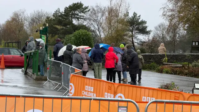 A group of people stand in a rainy road all wearing rain coats