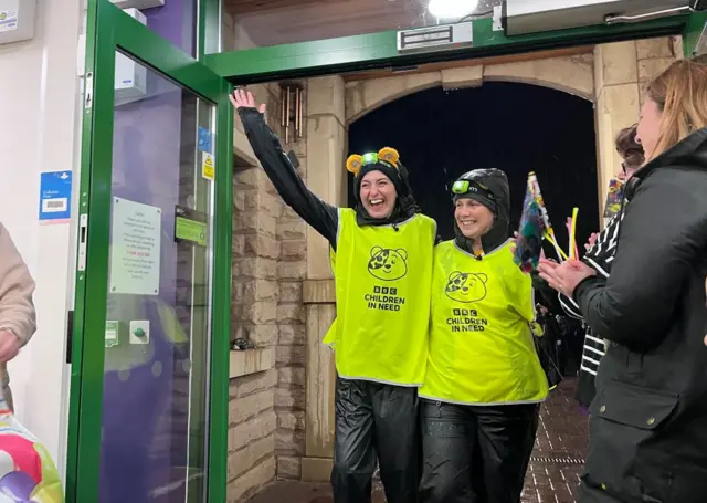 Two women in high wise with their hands in the air smiling