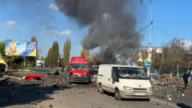 The aftermath of an apparent drone strike in the southern Ukrainian city of Chornomorsk where we can see two damaged vans, smoke and debris