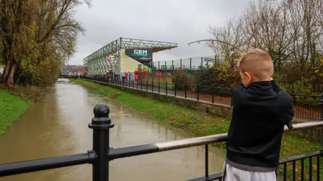 A young boy fishes in the river outside Lincoln's LNER Stadium