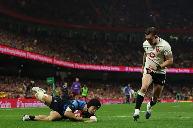 Japan's wing Kippei Ishida dives over the line to score