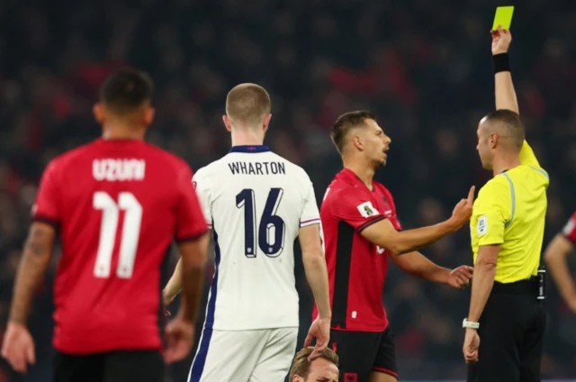 Albania's Ylber Ramadani is shown a yellow card by referee Marco Guida as England's Harry Kane