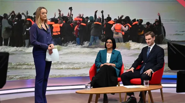 Laura Kuenssberg standing, Shabana Mahmood and Chris Phil sat down.