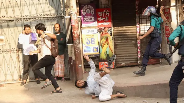 A police officer wields his baton against demonstrators to disperse them, ahead of the verdict on cases against the ousted Prime Minister Sheikh Hasina, in Dhaka, Bangladesh, November 17, 2025.