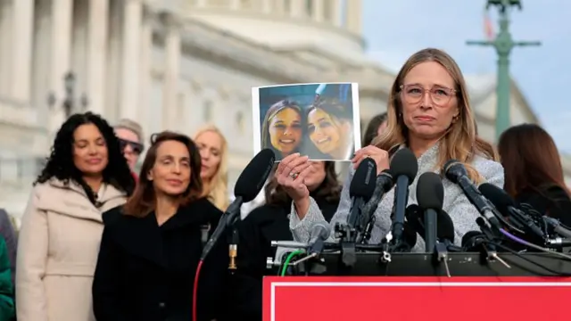 Annie Farmer holds up a photo of her younger self with her sister Maria Farmer