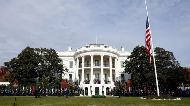 The White House, with lots of soldiers with American flags stood outside in ceremony, including a marching band