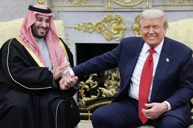Donald Trump and Saudi Crown Prince Mohammed bin Salman holding hands and smiling in the Oval Office.