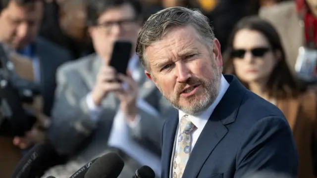 Republican Thomas Massie turns his head to the right while speaking during a media conference.
