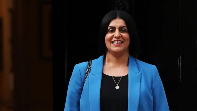 A smiling Home Secretary Shabana Mahmood wears a blue jacket and black top.