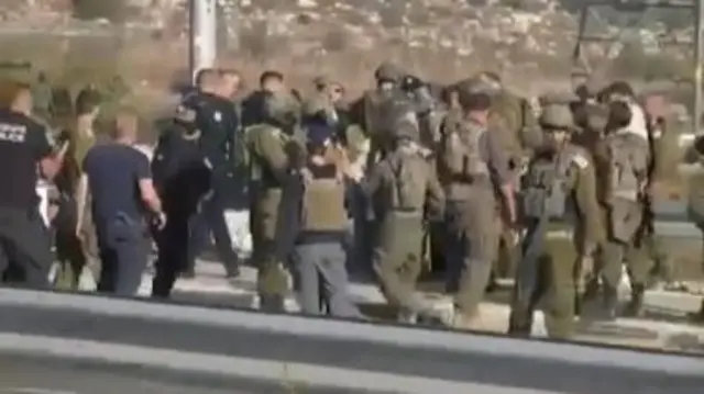 A large group of what appears to be Israeli soldiers and police at the scene of the reported attack