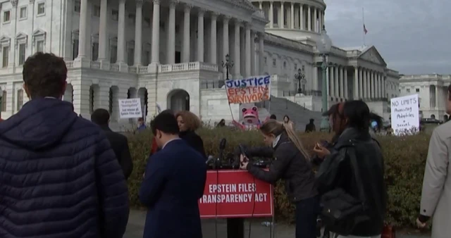People hold up signs in support of the Epstein files being released