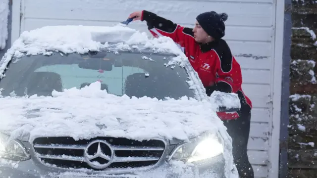 Woman scraping snow off car roof