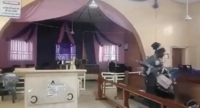 A man holding an assault rifle and handbags