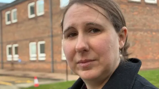 Julia Adams faces the camera, standing in front of court building
