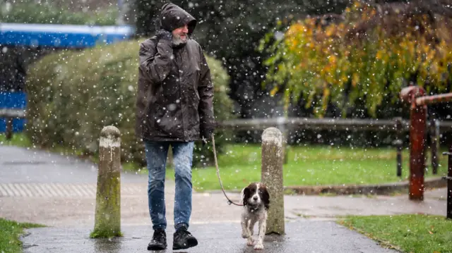 A man walks with his dog in the snow