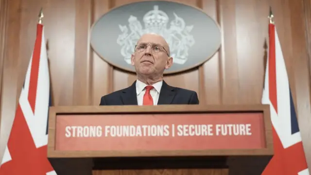 John Healey speaking at a podium which says: Strong foundations, secure future