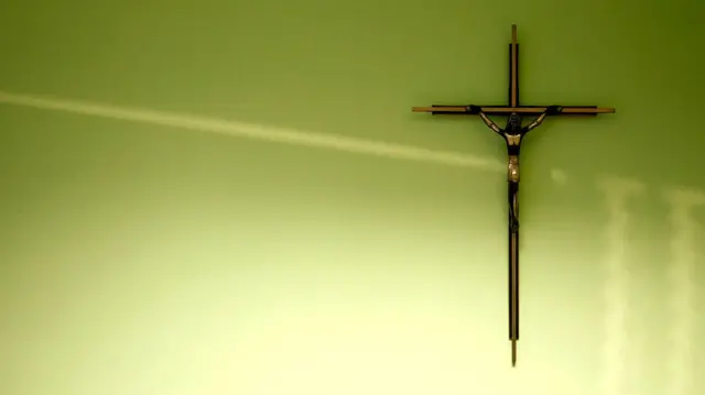 A crucifix hangs on a wall in a classroom.