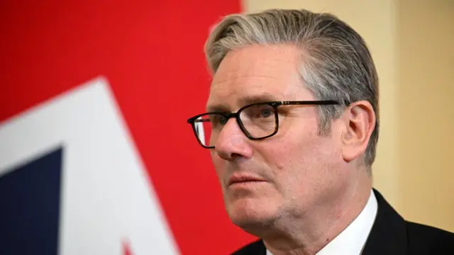 A file photo of Keir Starmer wearing a suit and standing in front of a union jack flag