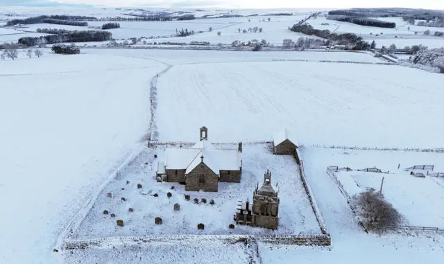A church and the surrounding fields blanketed in snow