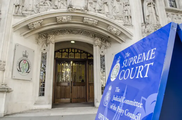 Exterior of UK Supreme Court, a large stone building with blue signage