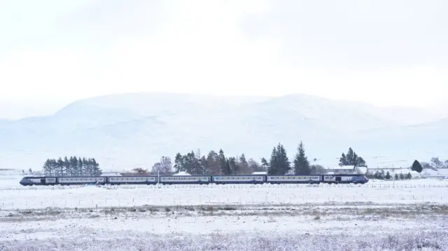 A train travelling surrounded by fields white with snow