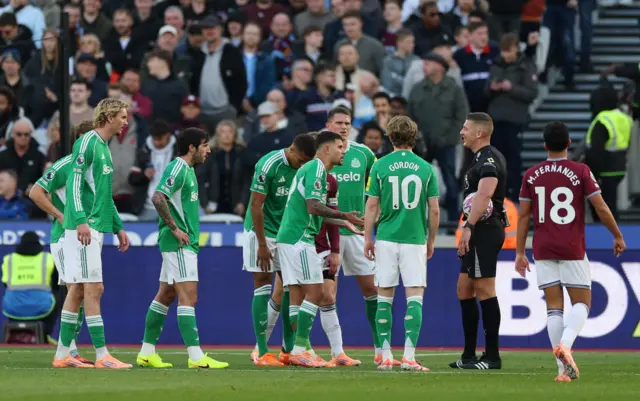 Newcastle players surround referee Rob Jones