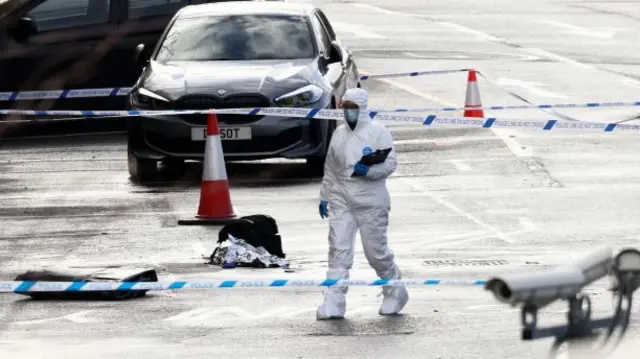 A forensic officer walks past a police cordon near Huntingdon Station