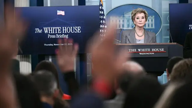 McMahon standing at podium in front of white house sign with reporters asking her questions
