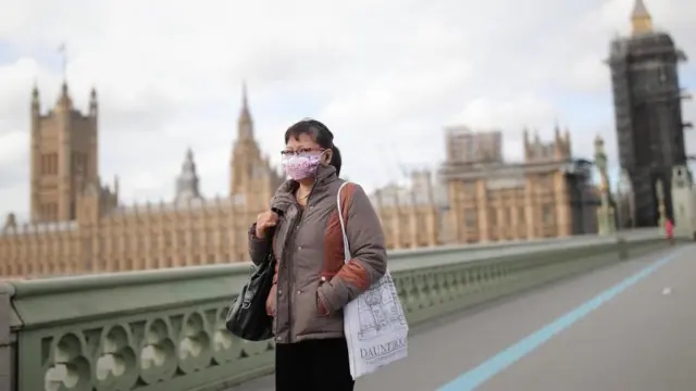 A woman in a face mask in London, with the Houses of Parliament in the background