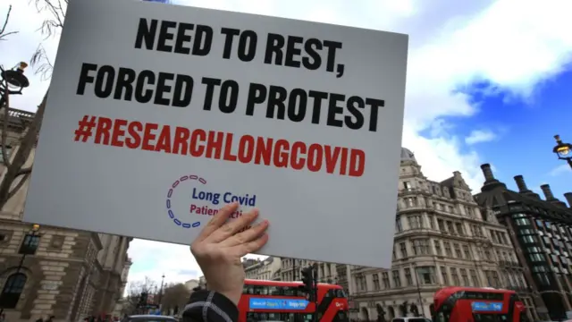 A protester holds up a placard demanding research into Long Covid-19 during a demonstration